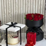 A bouquet of roses & a cake box with a gift necklace
